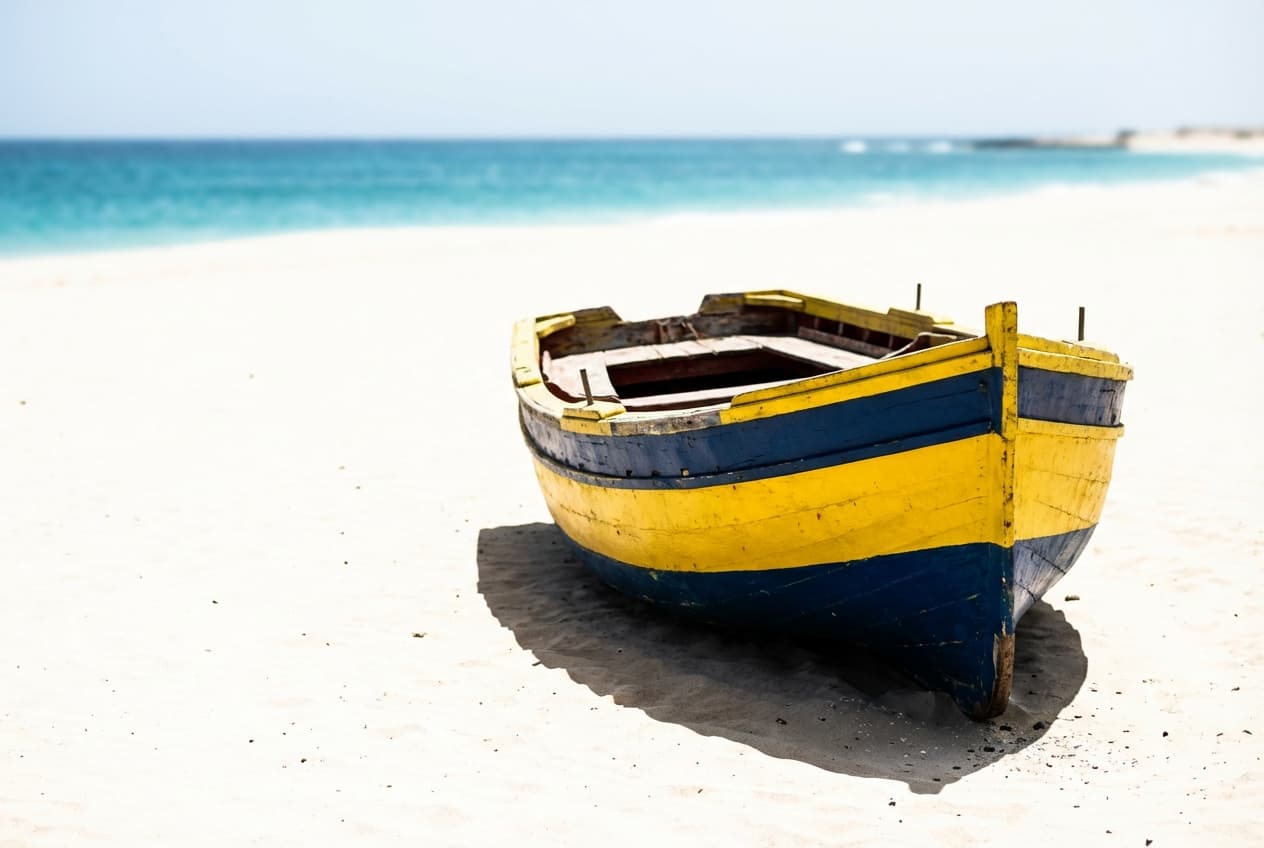 Bateau de pêche traditionnel coloré sur une plage de sable blanc au Cap-Vert
