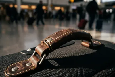 Gros plan minimaliste sur la poignée d'une valise de luxe dans un aéroport