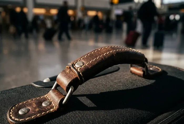 Gros plan minimaliste sur la poignée d'une valise de luxe dans un aéroport
