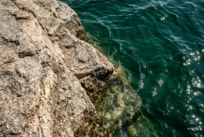 Détail minimaliste d'une vasque en granit avec de l'eau turquoise près d'Ajaccio