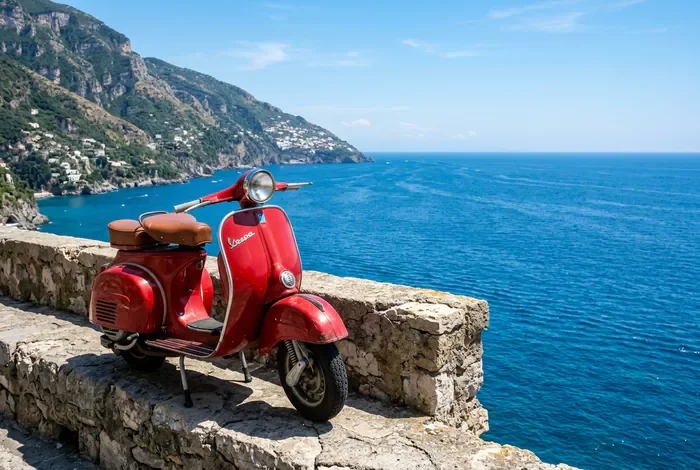 Vespa rouge iconique face à la mer Méditerranée sur la côte amalfitaine