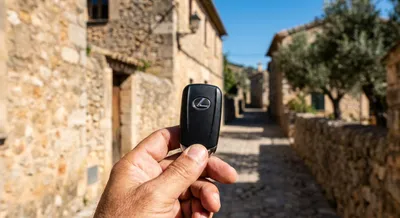 Gros plan sur une clé de voiture devant un village pittoresque majorquin.